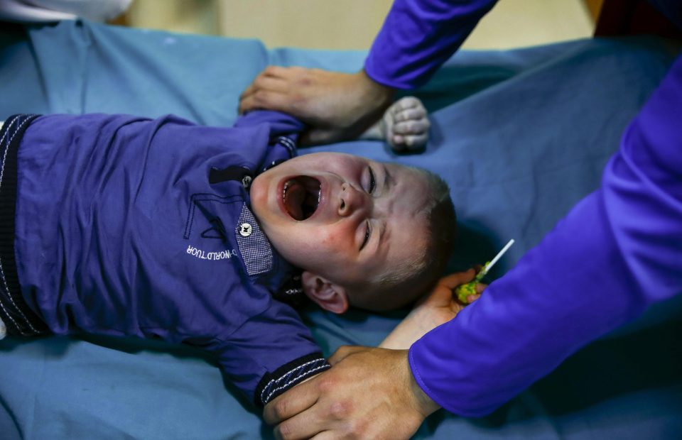  This youngster clutches a lollipop, which he will have to sooth him after the painful op