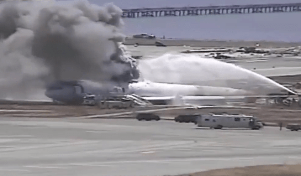 Fire engines douse the aircraft as black smoke billows out and into the sky 