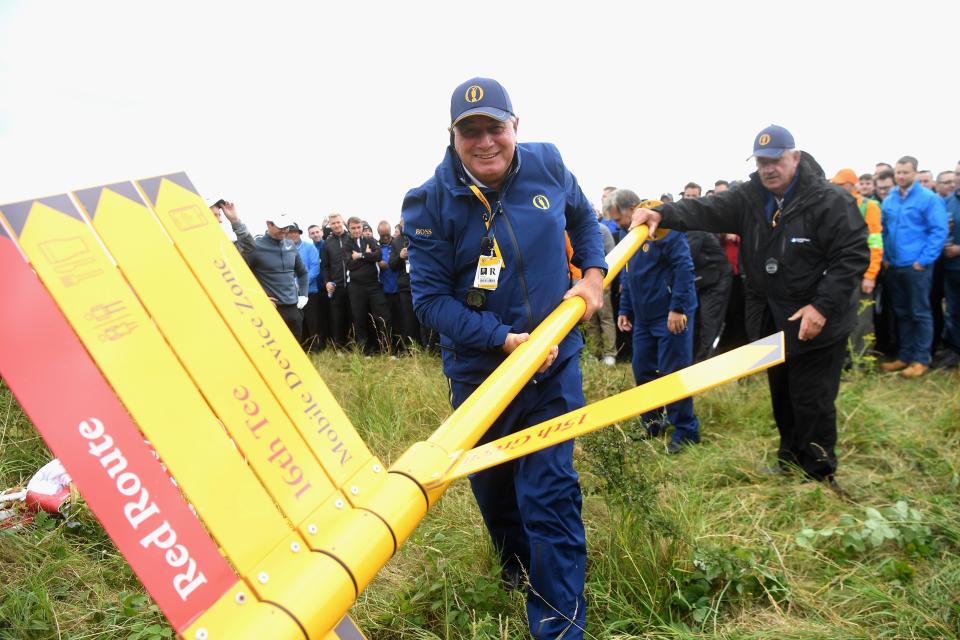  Officials move a sign out of the way for Rory McIlroy