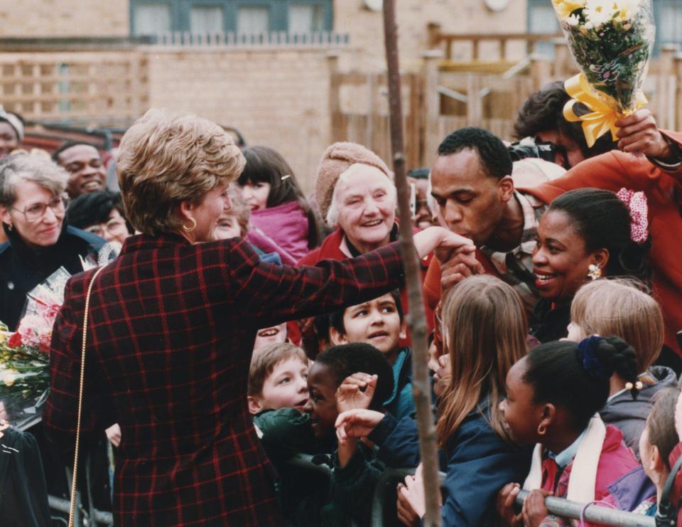  A man kisses Princess Diana's hand at the opening of a homeless hostel in South London