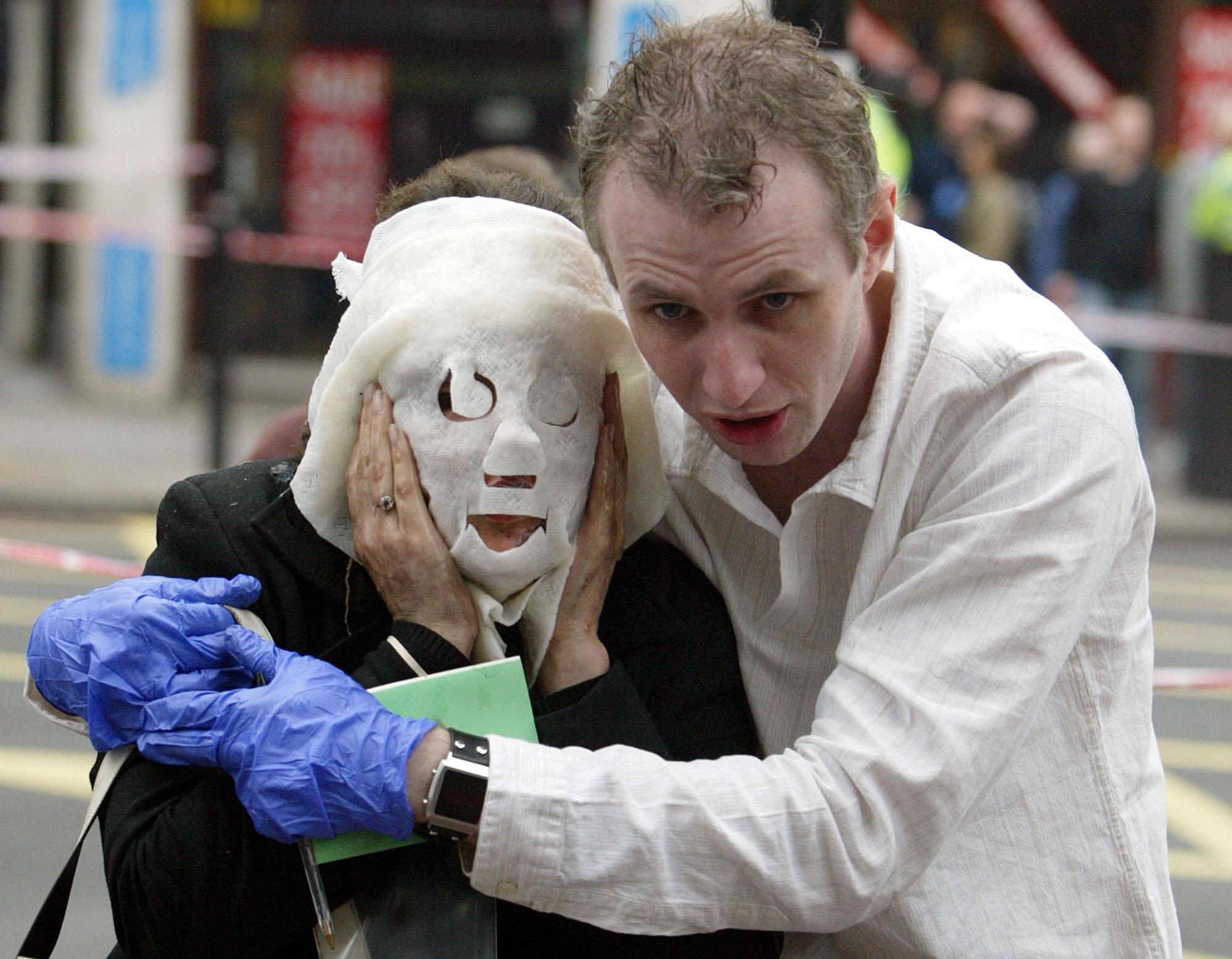 Paul Dadge, right, helps injured tube passenger Davinia Turrell away from Edgware Road tube station in London after the attack