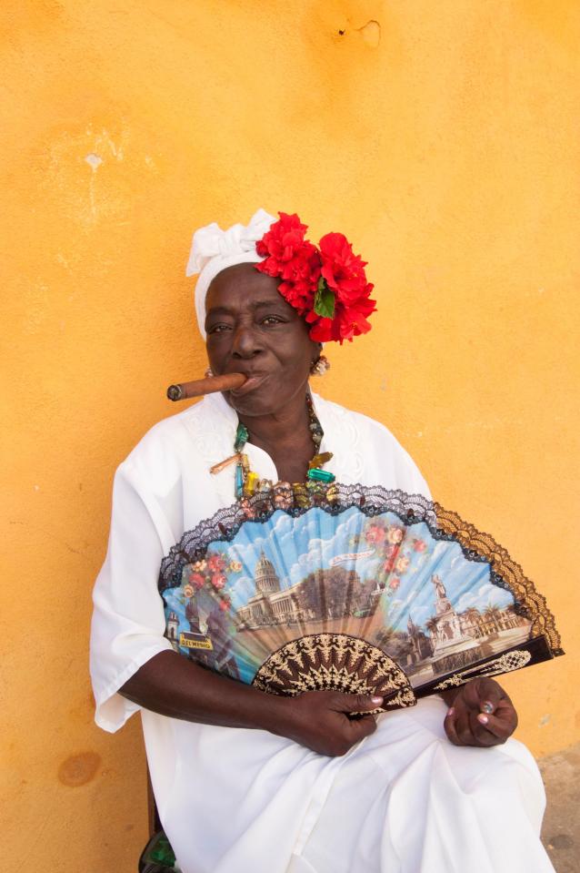  Cuban woman wearing a Santeria white dress smoking a big cigar