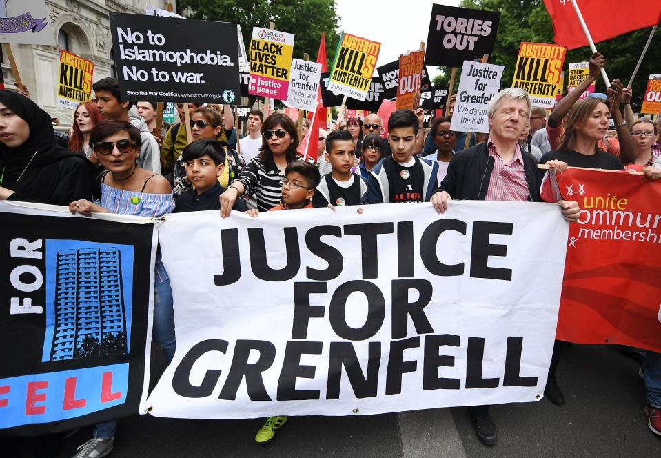  People with a banner reading 'Justice for Grenfell' during an anti-austerity demonstration outside Parliament in London