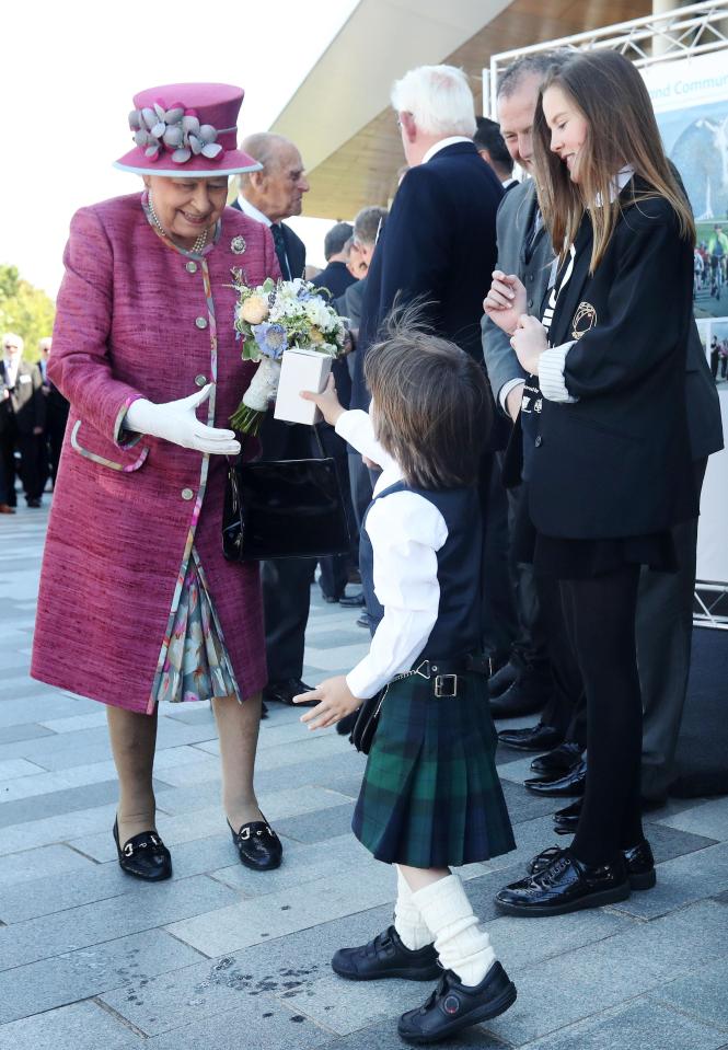  Five-year-old Sam Mitchell gives Queen Elizabeth II a present during her visit to Scotland which attracted hundreds of cheering spectators 