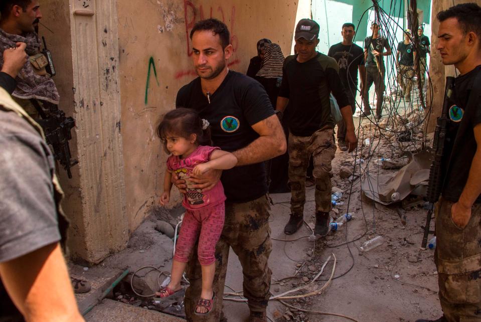 Iraqi forces take a child to safety as they advance on the ISIS positions which are starting to collapse