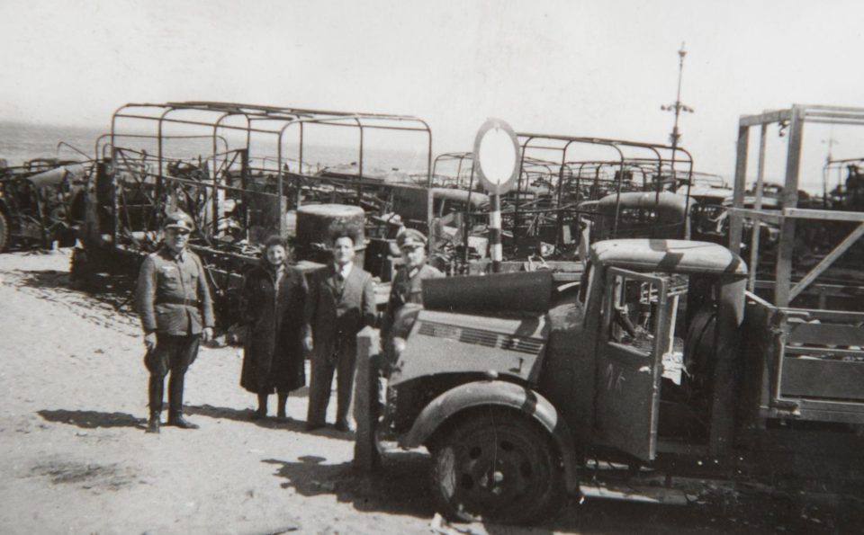  Officers stand in front of a fleet of burnt-out British army trucks which would have been used to off-load the thousands of the retreating troops days before