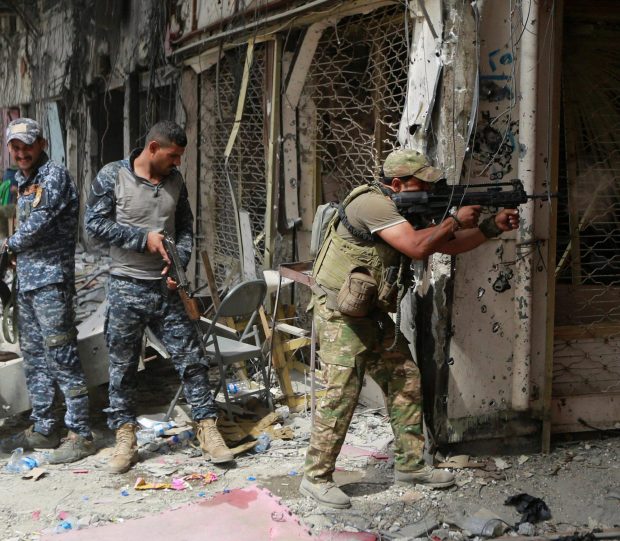 A member of the Emergency Response Division opens fire against ISIS militants in the Old City of Mosul