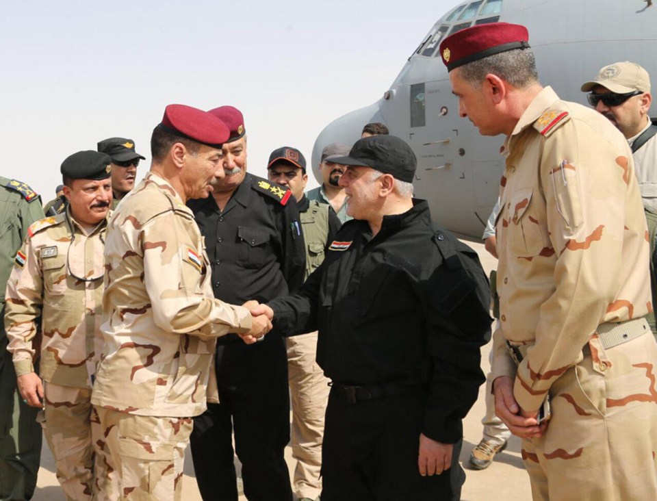 Iraqi Prime Minister Haider al-Abadi, centre, shakes the hands of his military commanders as he arrives in Mosul 