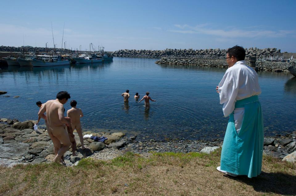  A Shinto priest (right) guides a group of men in a purification ritual before entering the island of Okinoshima