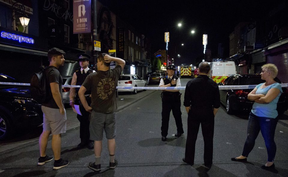  Onlookers pictured behind a police cordon as Camden High Street remained on lockdown in the early hours of Monday