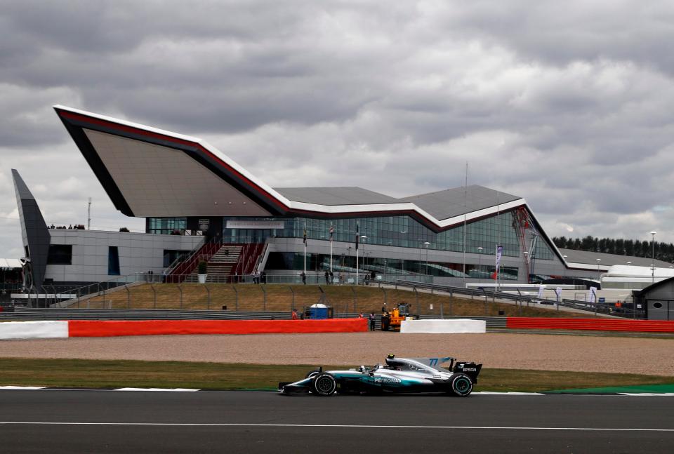 Valtteri Bottas makes his way past the imposing Wing building on an overcast day at Silverstone