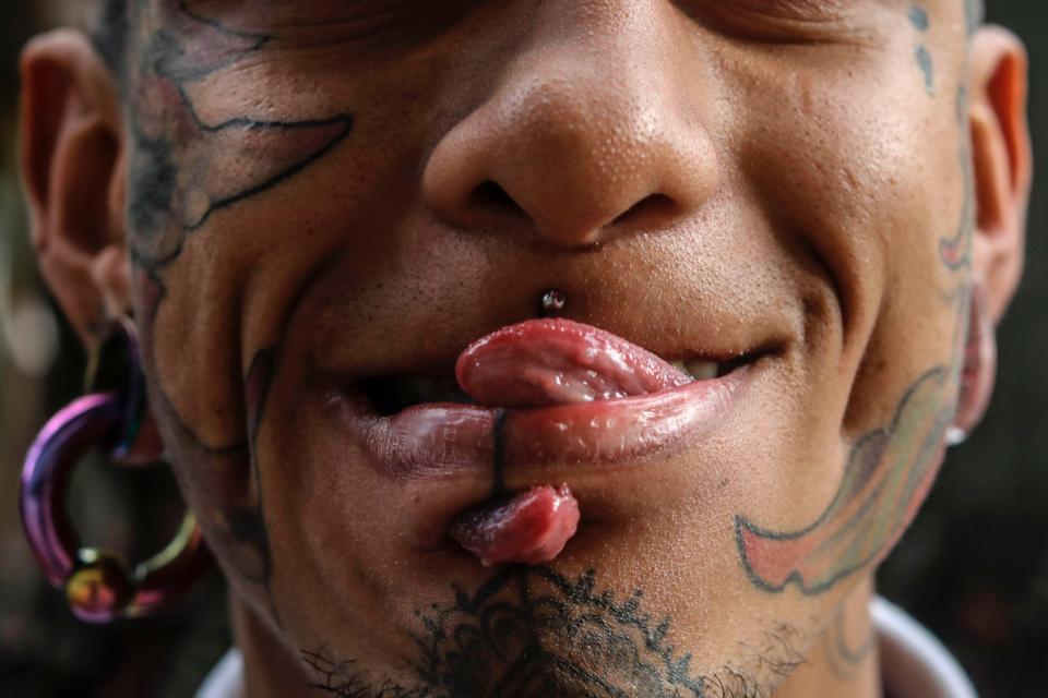  This man sticks his split tongue through a hole in his chin