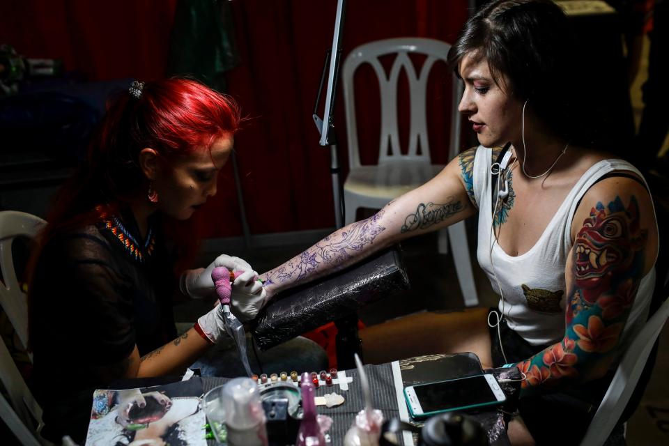  A girl sits patiently as an artist works on a stunning sleeve design