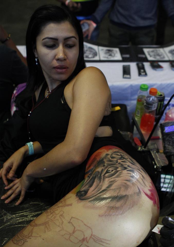  A girl admires her new wolf tattoo at the top of her leg