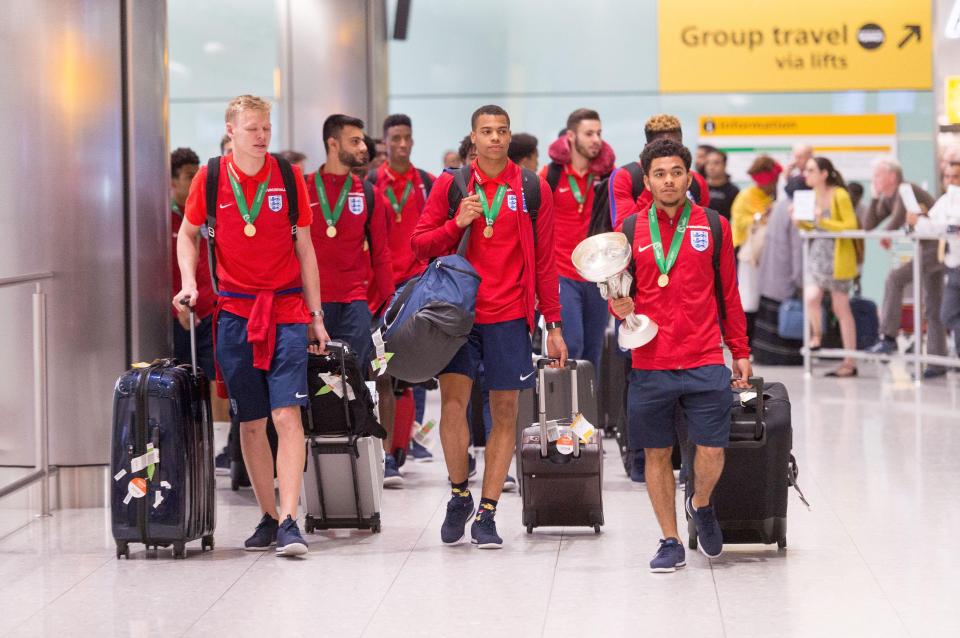  The England squad proudly pose with their winners medals on their return to London Heathrow airport