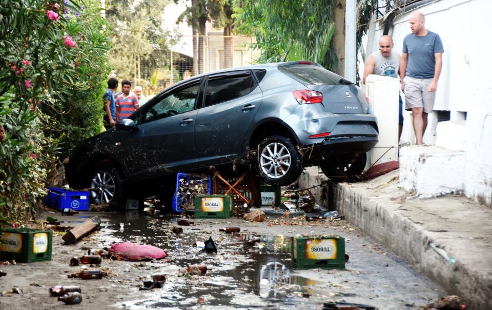  People walk past a damaged car following a sea surge in this Turkish coastal city of Mugla, Bodrum Province