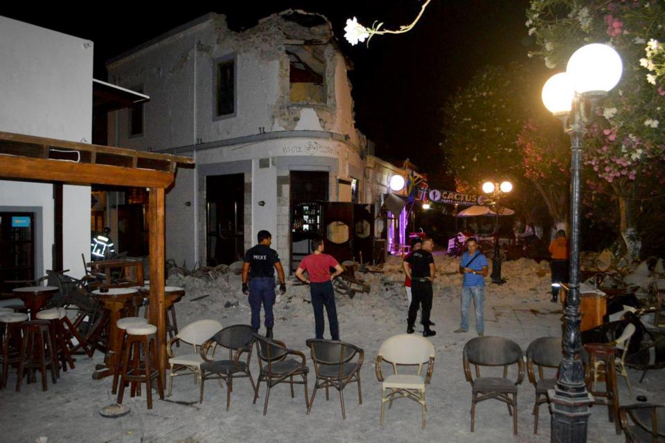  Partygoers stand outside a bar on Kos seriously damaged in the quake