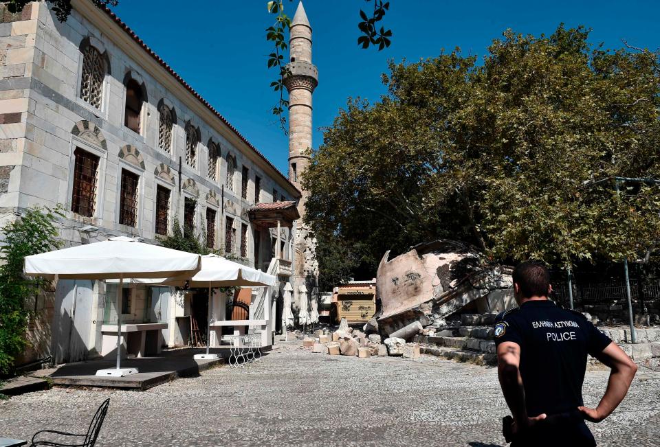  A policeman looks at a damaged mosque on the island