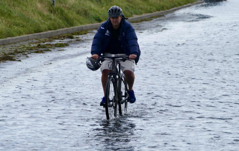  Cyclists ride through the flood waters at high tide at Keyhaven Marshes in The New Forest this morning