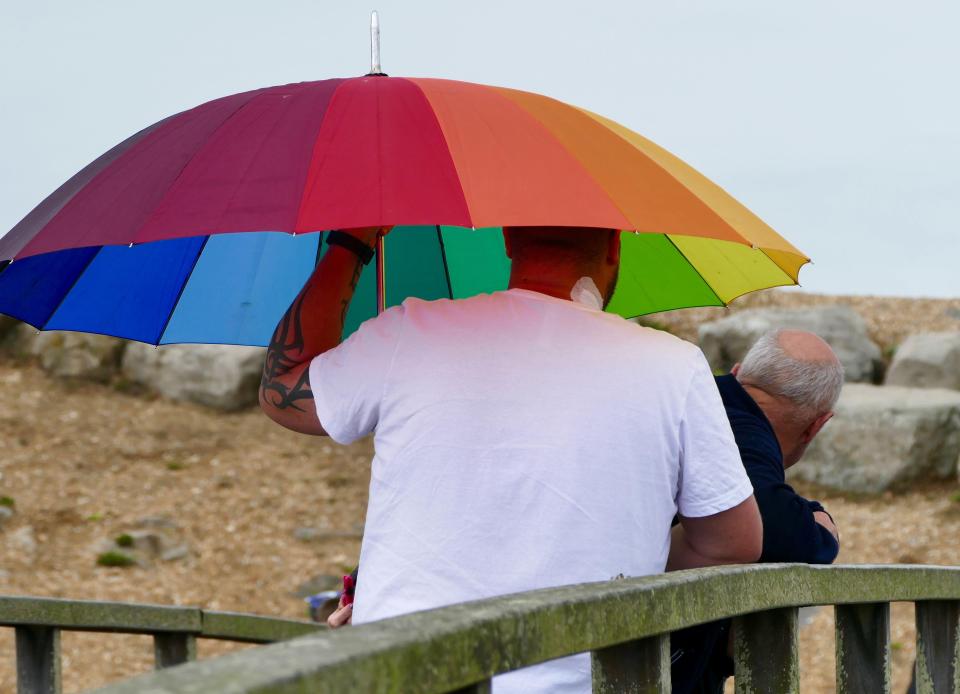  Crabbers take shelter under an umbrella today as the rain starts again at Hurst Cut in Hampshire