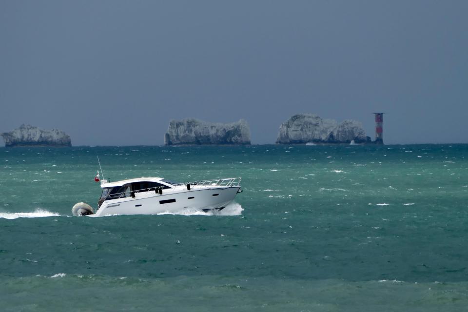  A speed boat races passed The Needles on the Isle of Wight under dark rain clouds today