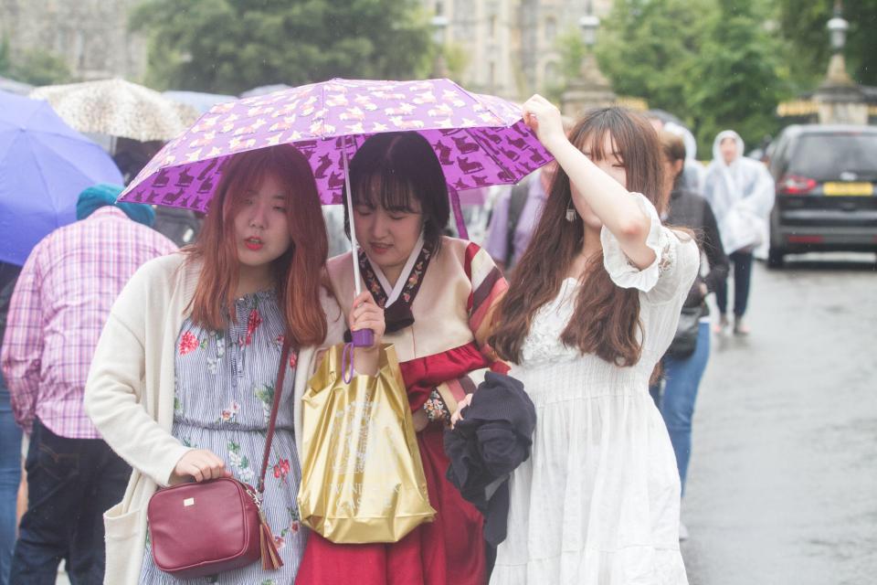  Tourists huddle under an umbrella in Windsor on a day of sightseeing