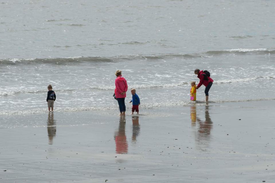  Big macs and tides ... parents and children head to the beach in waterproof jackets in Lyme Regis