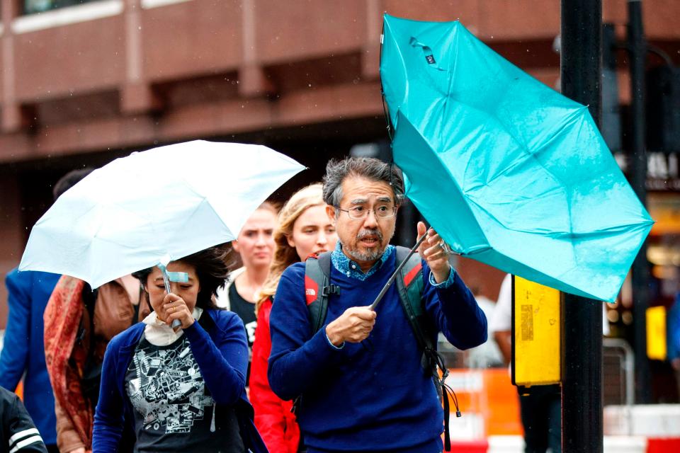  Tourists use umbrellas to shelter from the rain as inclement weather hits central London this afternoon