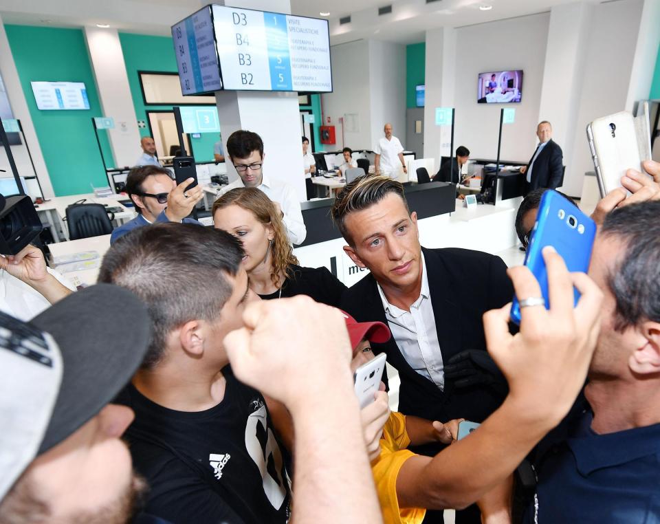 The Italian poses for a selfie with fans as he arrives to undergo his medical