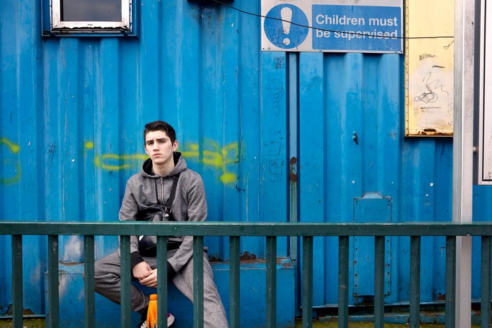 Jerry (13) sits in front of the site’s makeshift school building. He described how he felt 'much safer' on the site