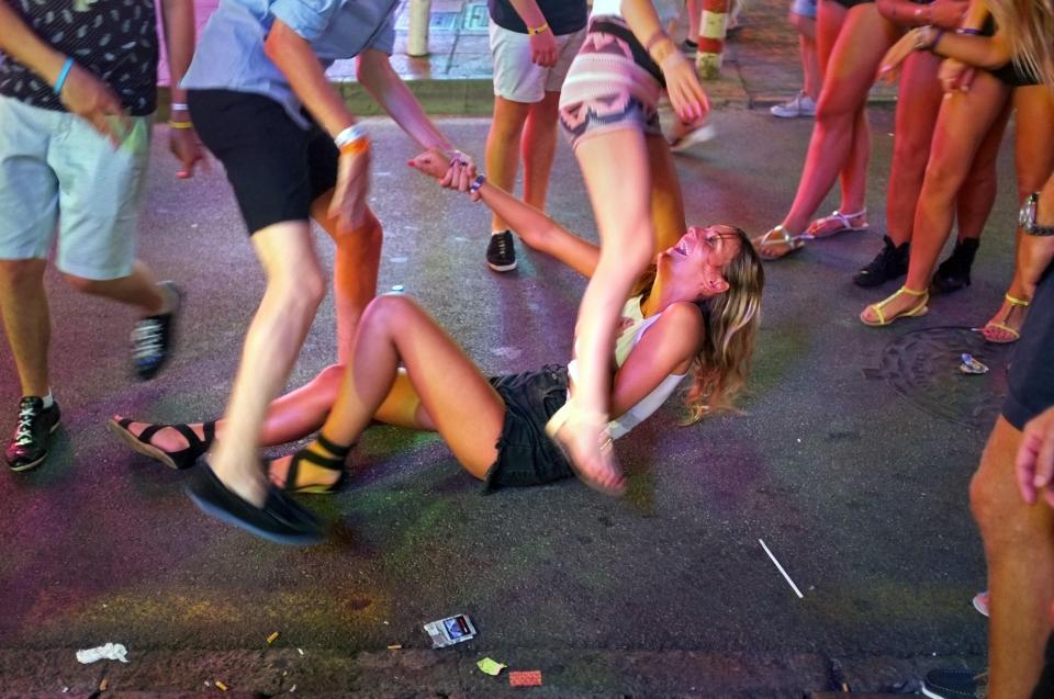 A girl laughs as she sits on the pavement in Magaluf's party zone Punta Ballena