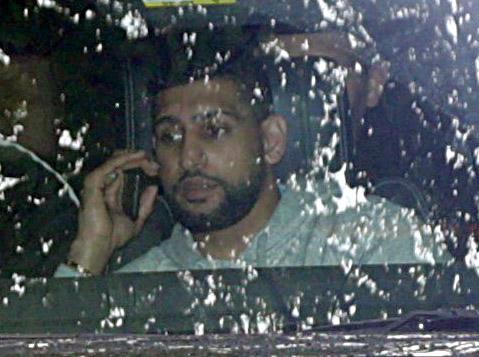 Amir Khan speaks on the phone as he visits the family home today after flying back from Dubai