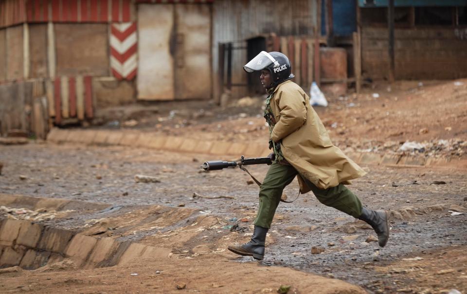  A lone riot cop charges towards protesters armed with a tear gas gun