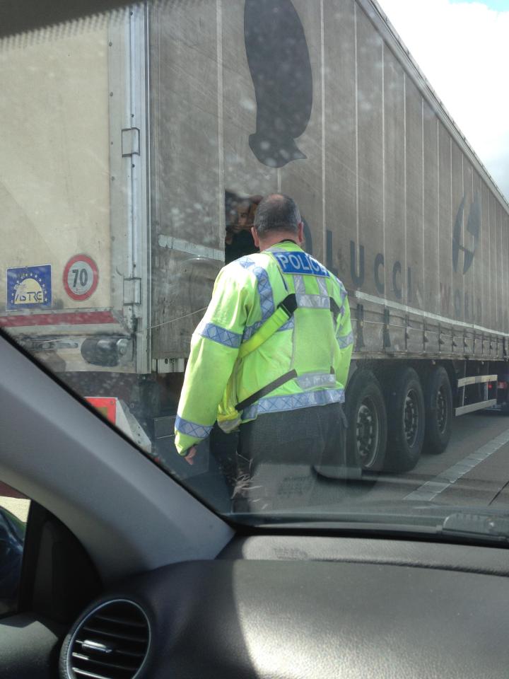  A migrant looks out of the lorry back at a policeman