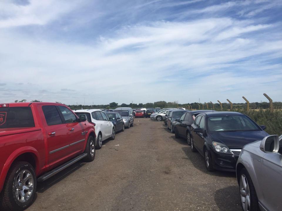  Luxury cars are parked bumper to bumper on a dirt track