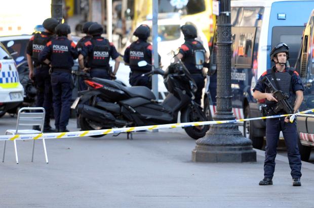 Armed police stand in a cordoned off area after a van ploughed into the crowd in Barcelona