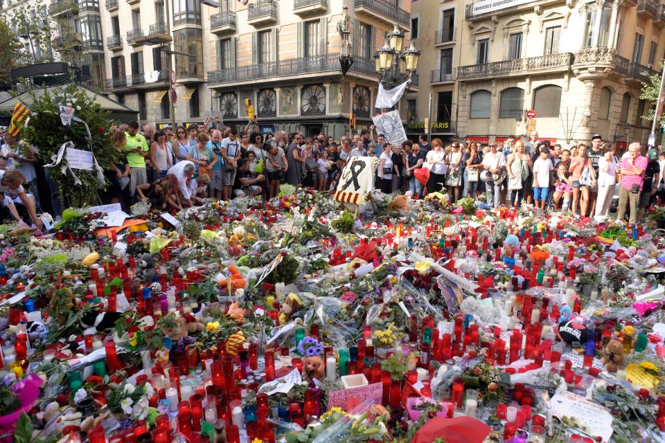  People stand next to flowers, candles and other items set up on the Las Ramblas boulevard in Barcelona as they pay tribute to the victims of the Barcelona attack