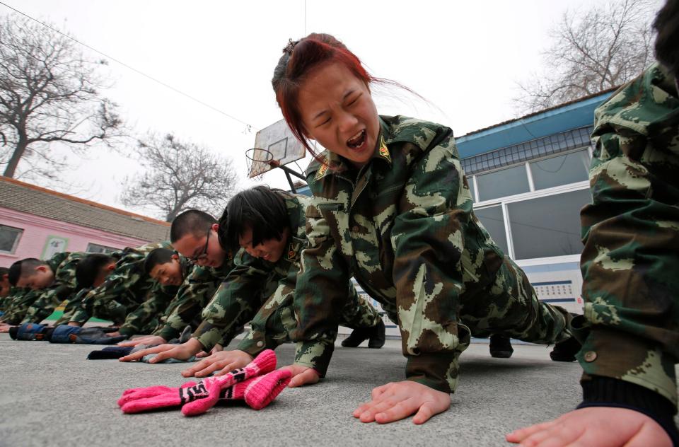  A young girl winces as she is forced to carry out press-ups during drill at the Qide Education Center in Beijing