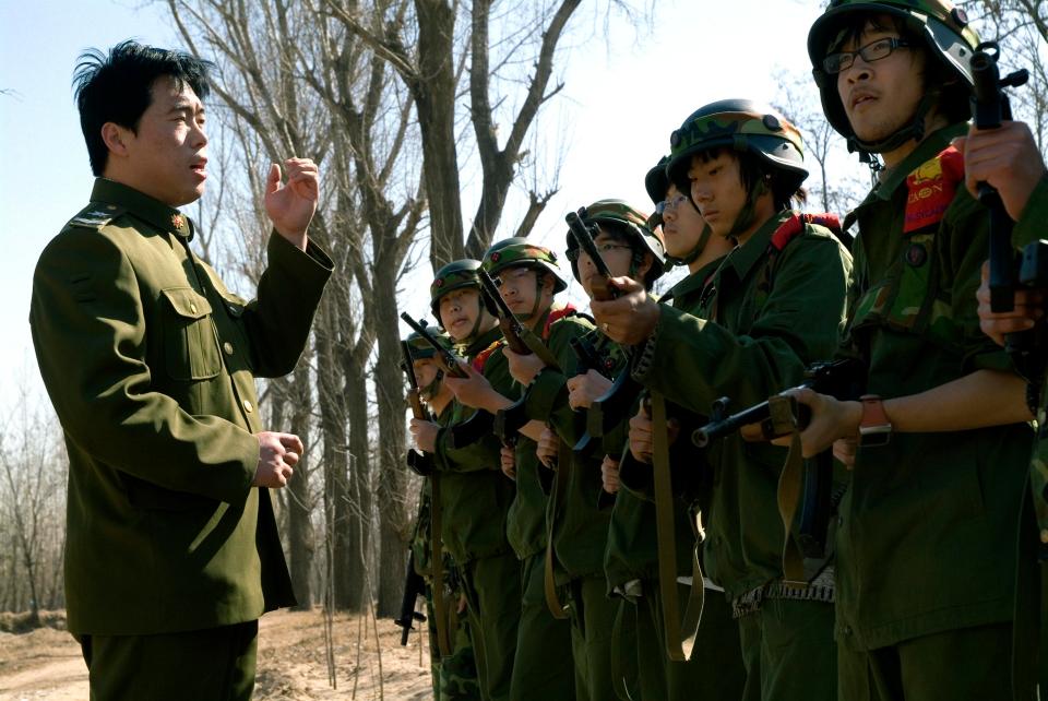  A group of teenagers at an internet addiction camp in Daxing stand with weapons as part of their military training