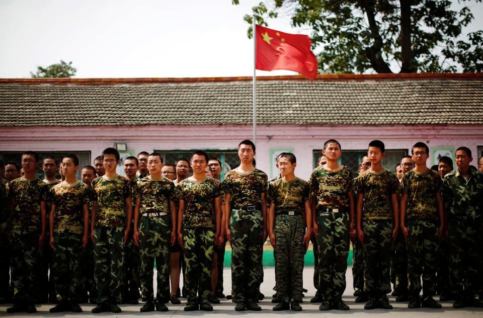  All patients at the camps must take part in military drill. Pictured are teenagers standing to attention next to the Chinese national flag at the Qide Education Center