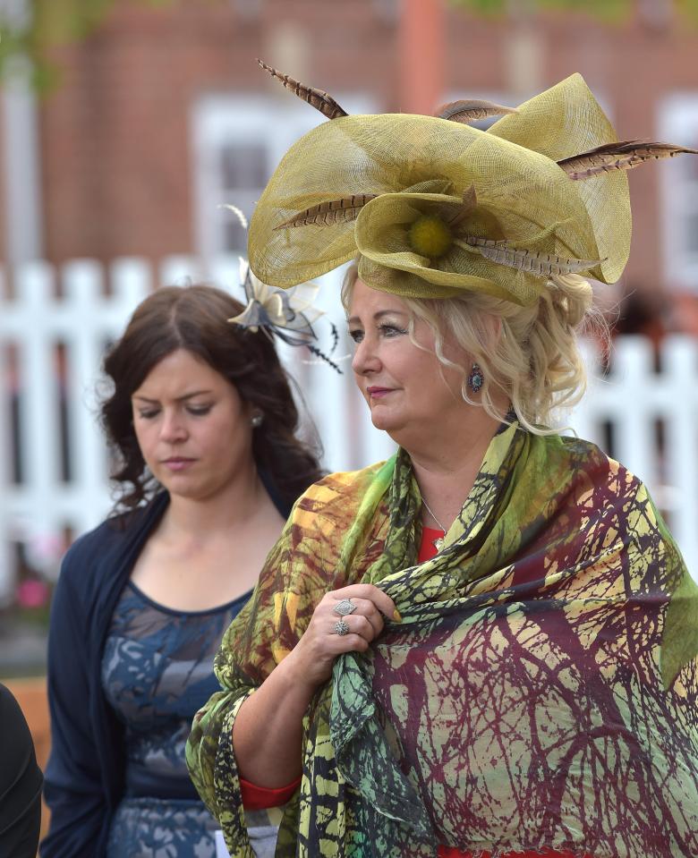  A reveller looked chic in a deep green hat that featured a giant flower and a patterned shawl