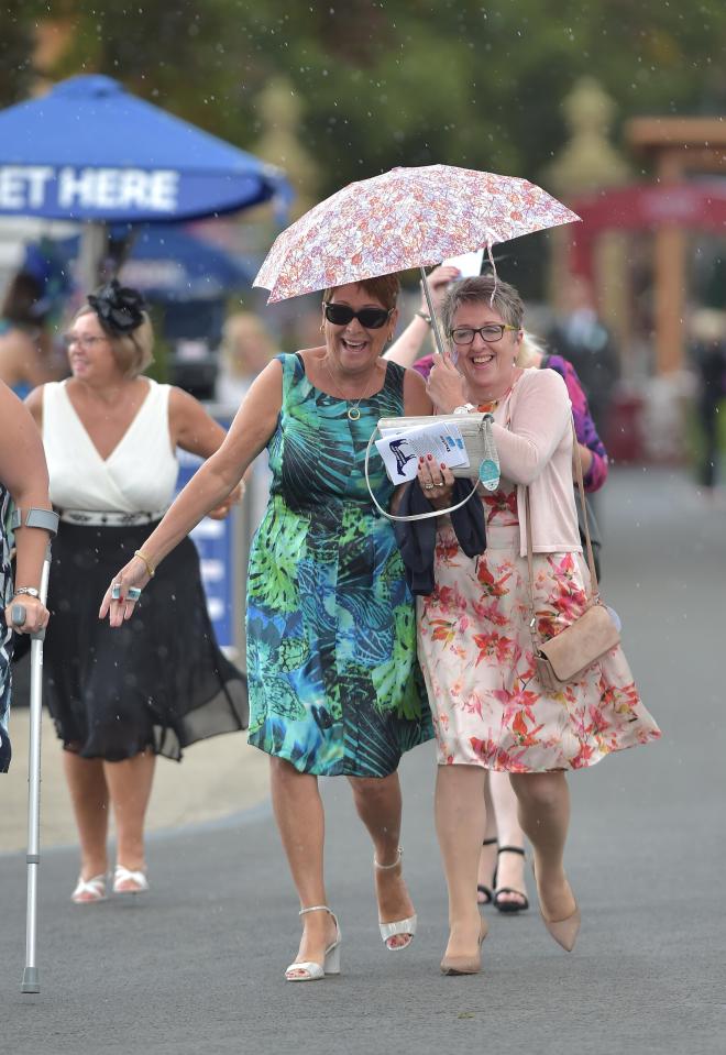  Pals were spotted in fits of giggles as they tried to shelter their pretty outfits from the elements