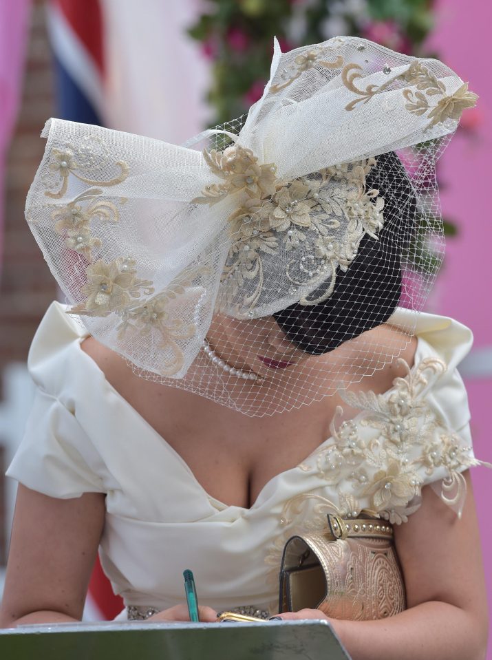  A woman in an off-the-shoulder cream and gold dress is pictured filling in her race card