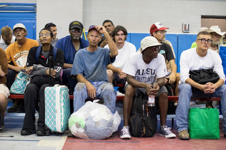  People sit with their packed up belongings as they evacuated from their homes