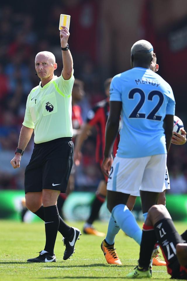  Mike Dean dishes out a yellow card during the game