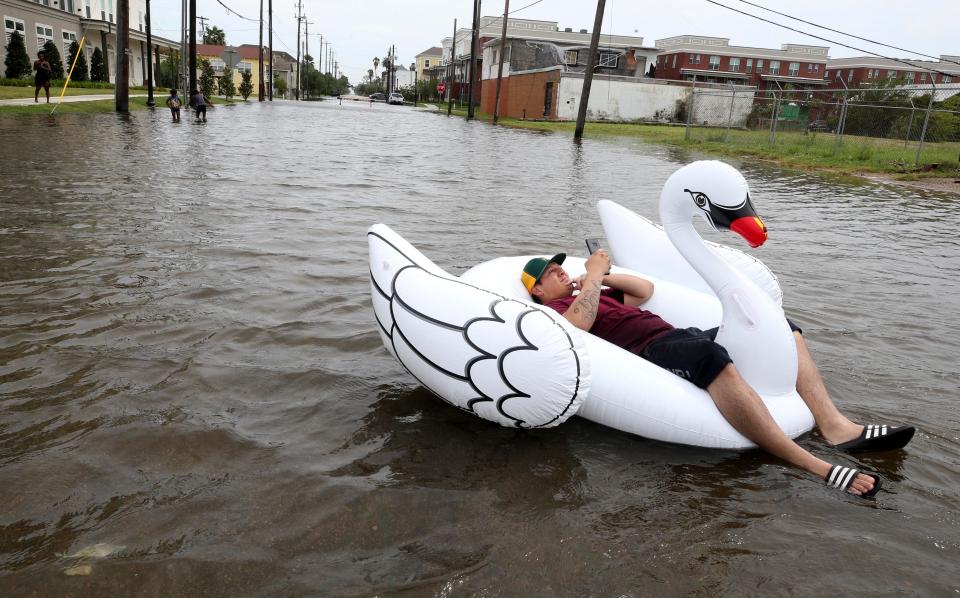  A man rests on an inflatable swan during intense floods