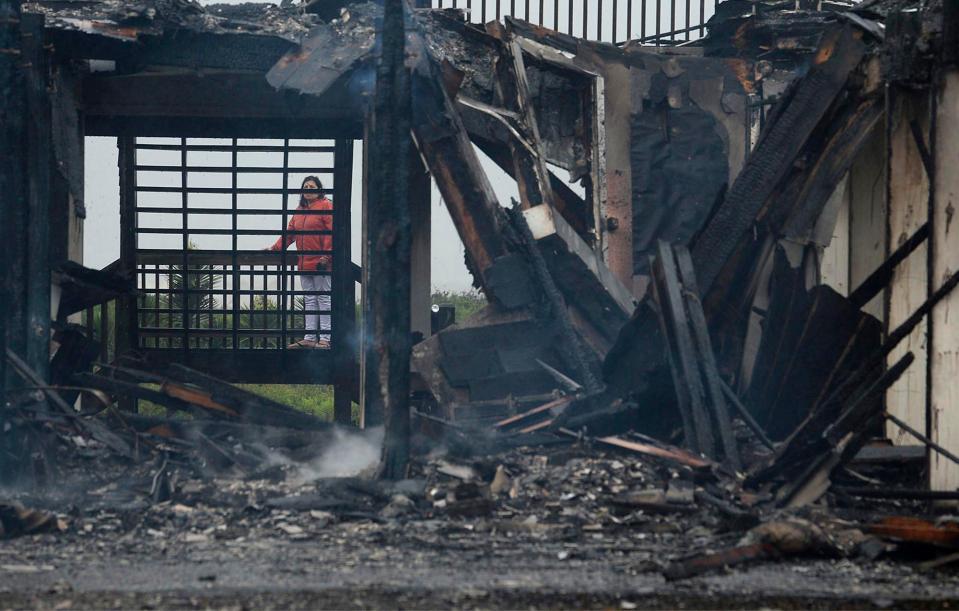  A beach cabin looks over the remains of their home Saturday after fire destroyed it and two others