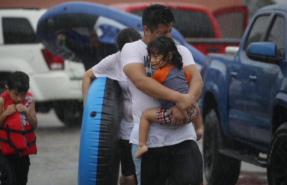 Mario Qua holds his daughter Wilson as they evacuate their flooded home