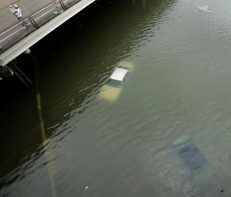 People look at submerged cars on a freeway flooded by Tropical Storm Harvey