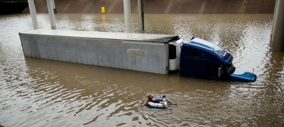 A man floats past a truck submerged on a freeway in Houston